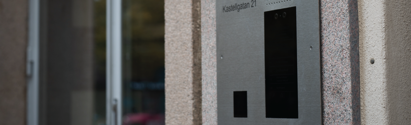 En porttelefon som är integrerad i fasaden och graverad med texten "BRF Kastellgatan 21"